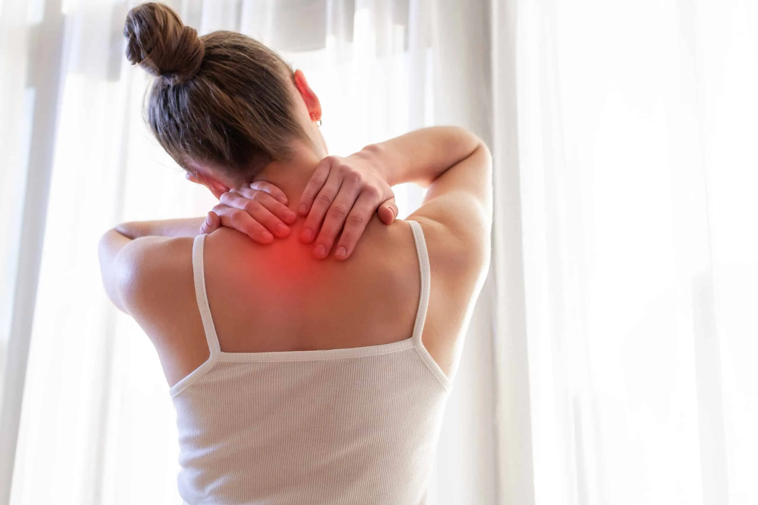 Femme se tenant la nuque et les épaules, avec une zone de douleur représentée en rouge