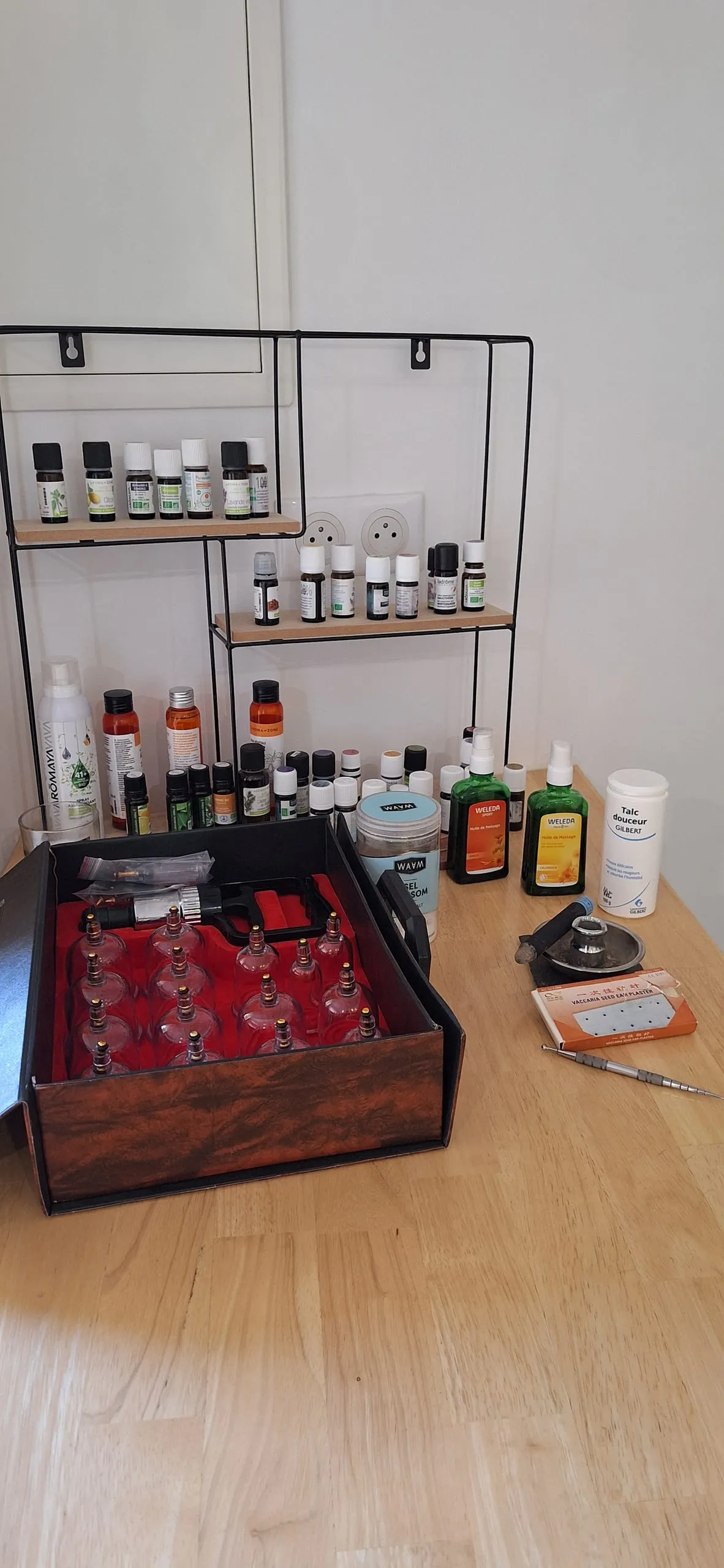 Coffret de ventouses en verre, huiles essentielles et matériel de moxibustion posés sur le plan de travail du cabinet.